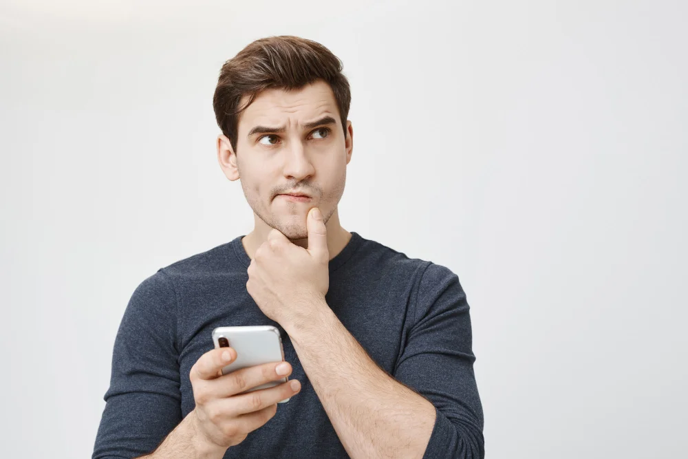 puzzled-thoughtful-man-thinking-while-holding-smartphone-1024x683
